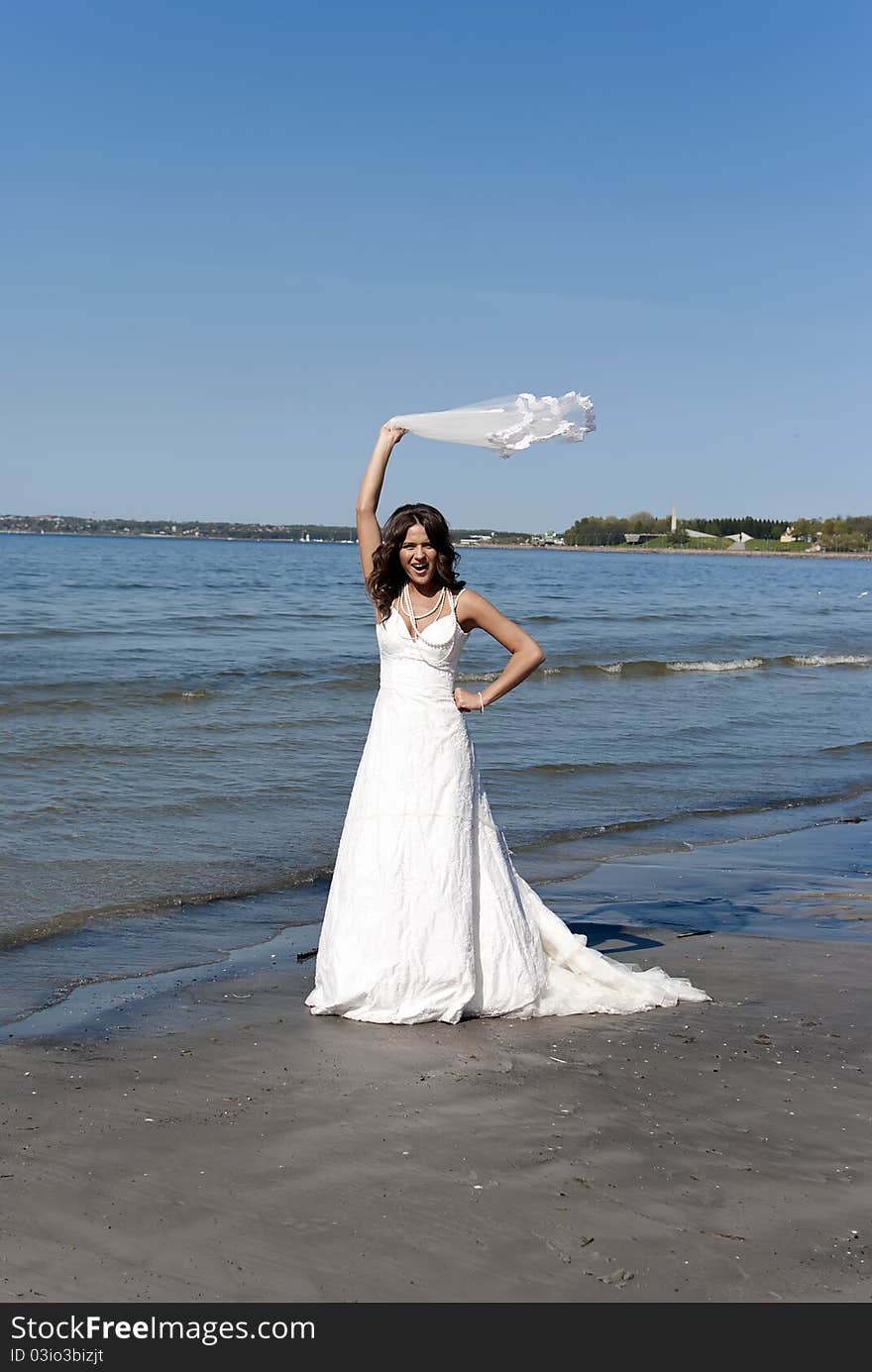 Bride twirling the veil near the sea