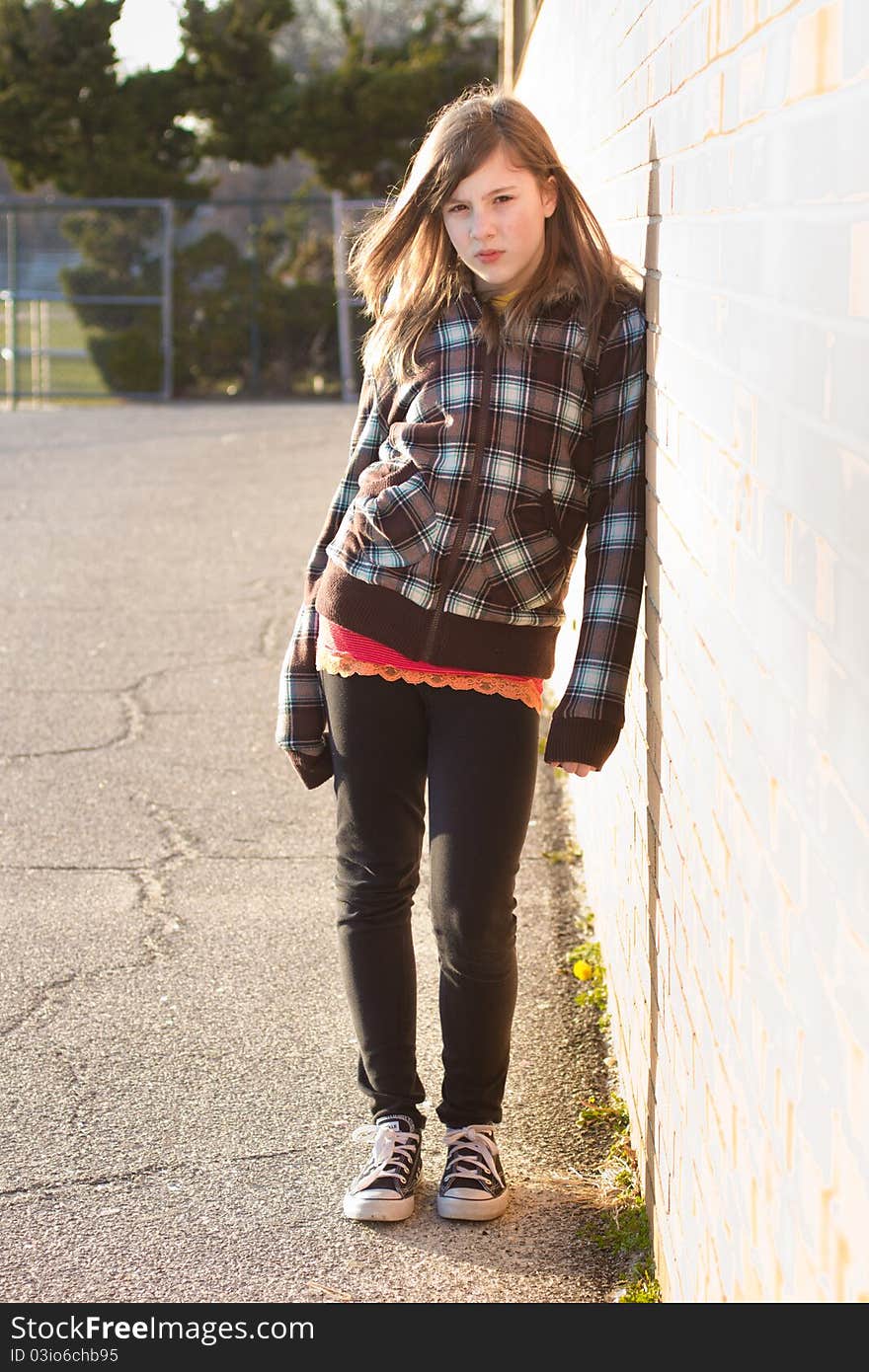 Portrait of a cute teenage girl leaning on a brick wall in the schoolyard. Portrait of a cute teenage girl leaning on a brick wall in the schoolyard