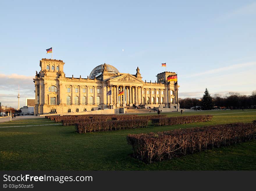 Warm evening sunlight illuminating the mighty Reichstag parliament with clear blue sky and flags flying. Warm evening sunlight illuminating the mighty Reichstag parliament with clear blue sky and flags flying.