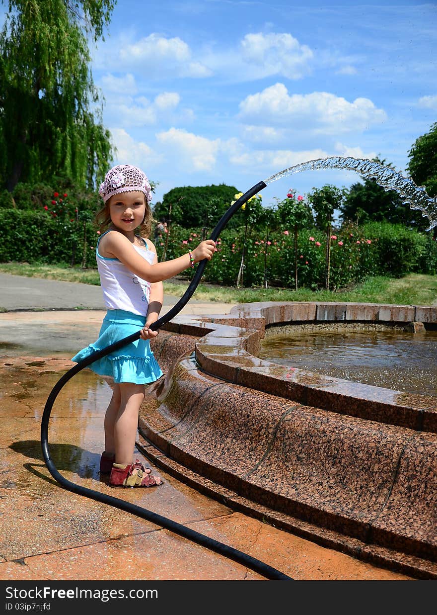 Little girl with a hose near the fountain