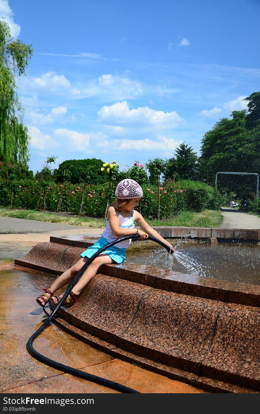 Little girl with a hose near the fountain