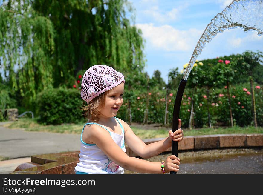 Little girl with a hose near the fountain