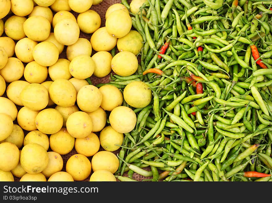 Lemon and chillies, displayed in a vegetable shop. These two ingredients are used to prepare the most spicy and popular Indian pickle. Lemon and green chillies are also hung at doors of Hindu people to keep all evil spirits away. Lemon and chillies, displayed in a vegetable shop. These two ingredients are used to prepare the most spicy and popular Indian pickle. Lemon and green chillies are also hung at doors of Hindu people to keep all evil spirits away.