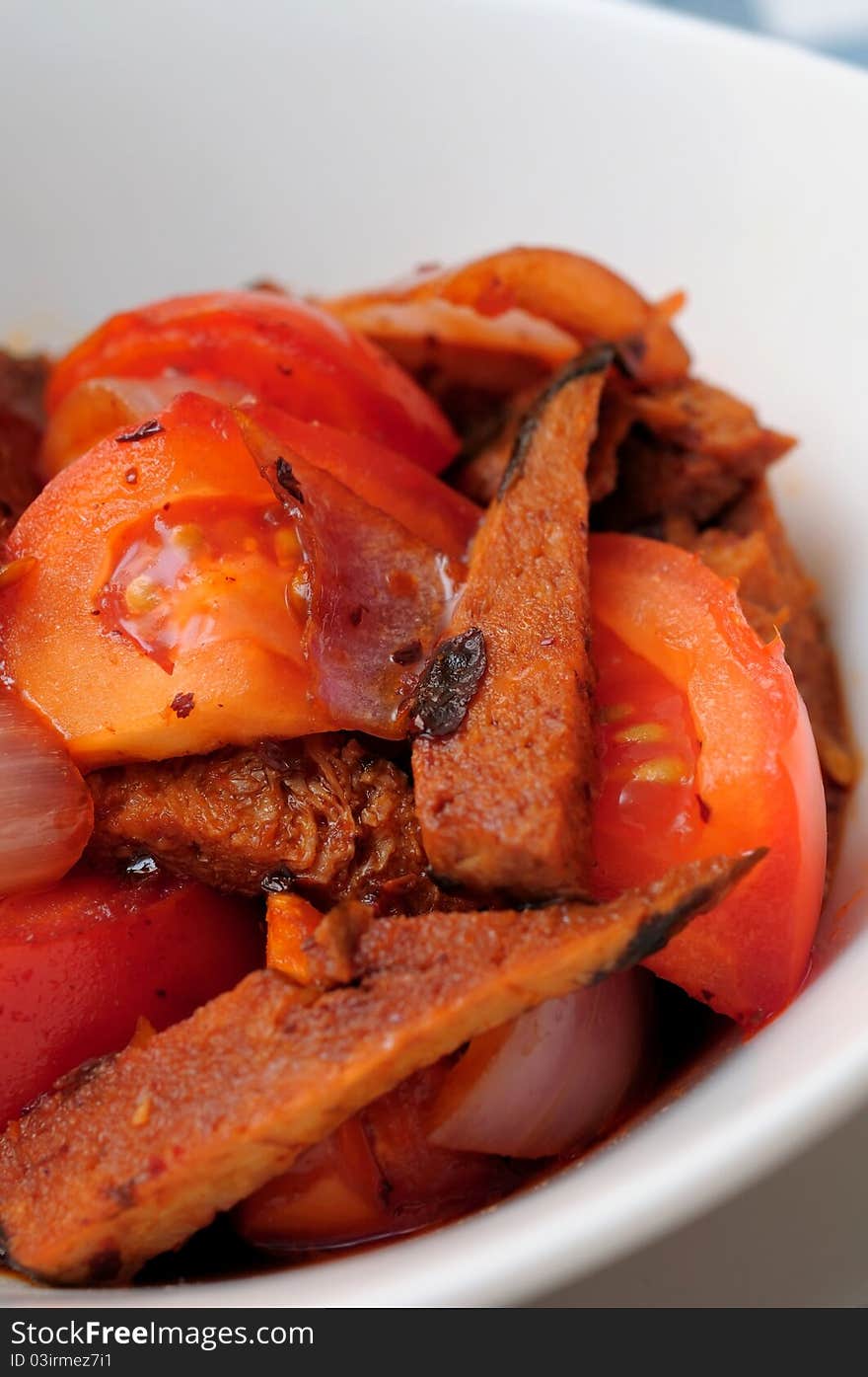 Macro shot of meat slices cooked with cut tomatoes. Macro shot of meat slices cooked with cut tomatoes.