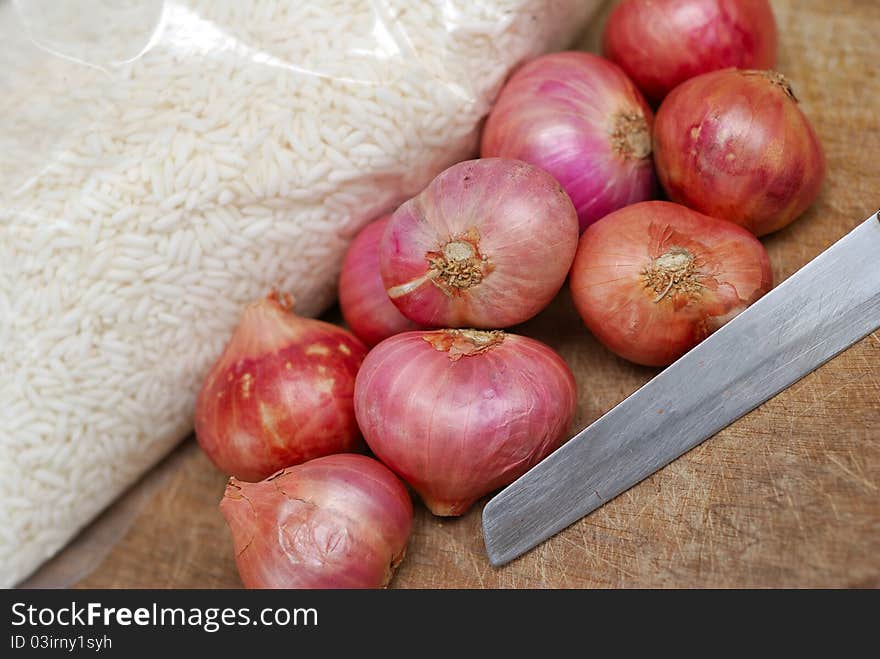 Fresh onions and knife on cutting board.