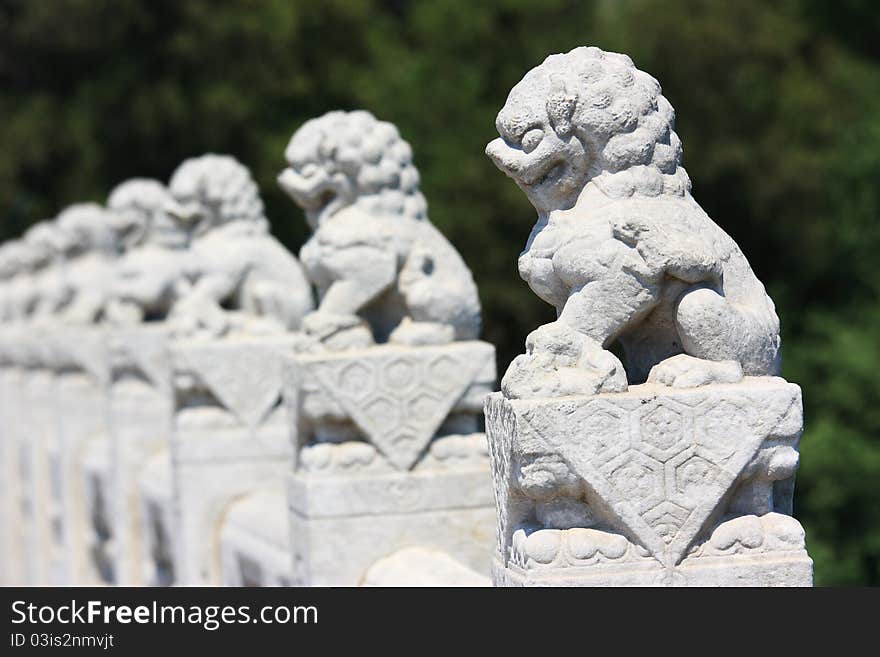 In the Summer Palace, these 544 carved white marble lions, in distinctive postures, sit at the column of the parapets on the 17-arch Bridge, which looks like a rainbow arching over the lake water.Beijing, China. In the Summer Palace, these 544 carved white marble lions, in distinctive postures, sit at the column of the parapets on the 17-arch Bridge, which looks like a rainbow arching over the lake water.Beijing, China