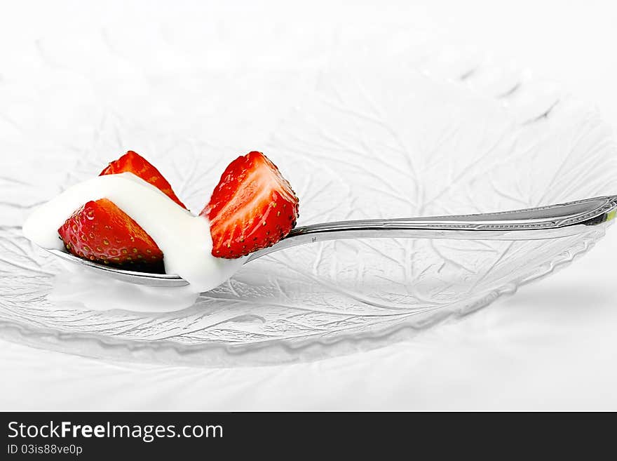 Red strawberry and white ice cream on spoon on white background