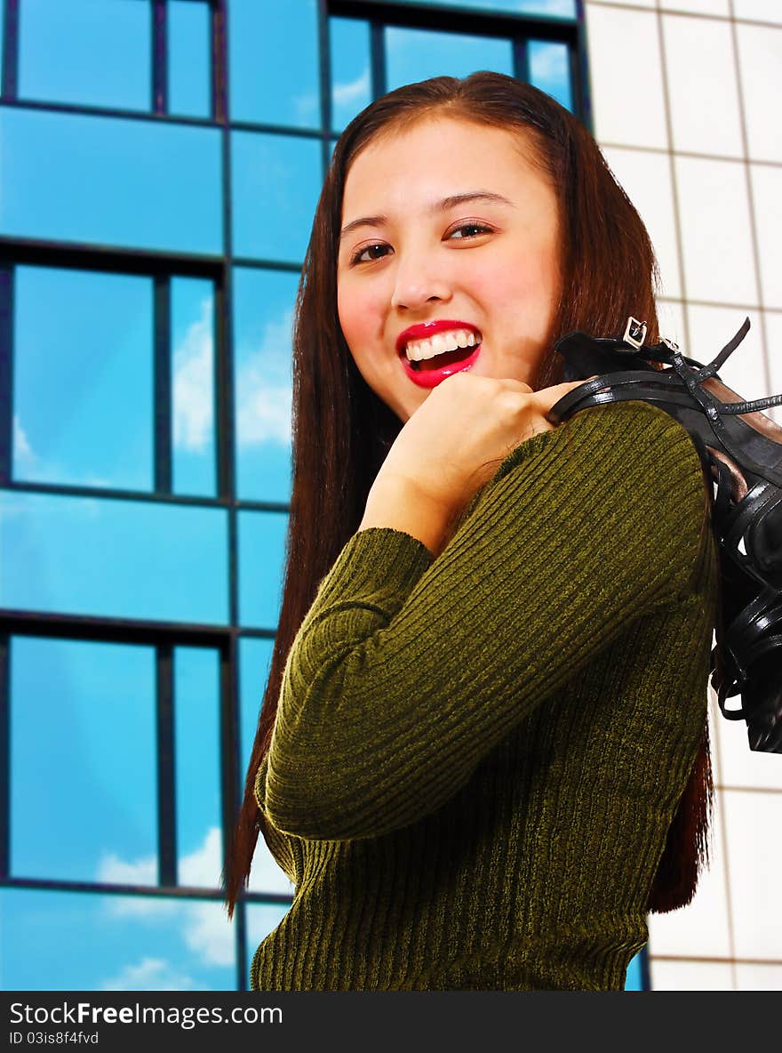 Attractive young woman smiling and standing in front of a reflective office building. Attractive young woman smiling and standing in front of a reflective office building