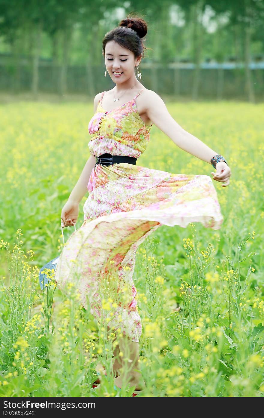 Charming Asian girl strolling in summer rape field. Charming Asian girl strolling in summer rape field.