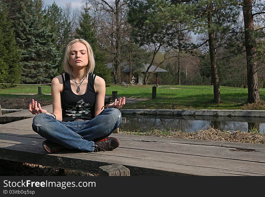 Pretty blond girl, meditating at Japanese garden. Pretty blond girl, meditating at Japanese garden