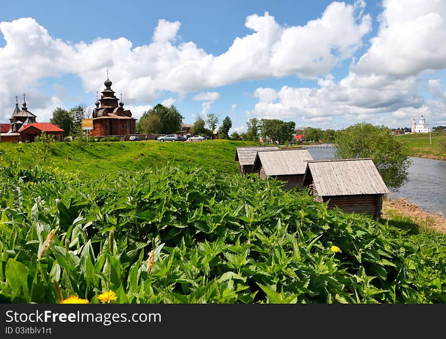 Bed of nettles at Kamenka river bank in ancient russian town Suzdal against old wooden church. Bed of nettles at Kamenka river bank in ancient russian town Suzdal against old wooden church.