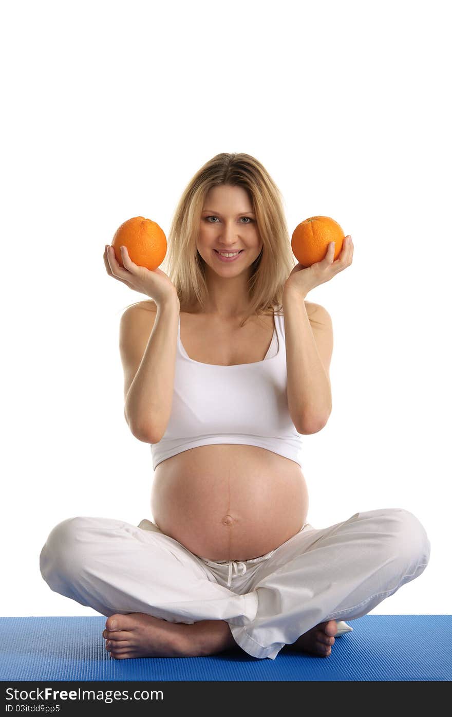 Pregnant woman practicing yoga and keeps oranges isolated on white