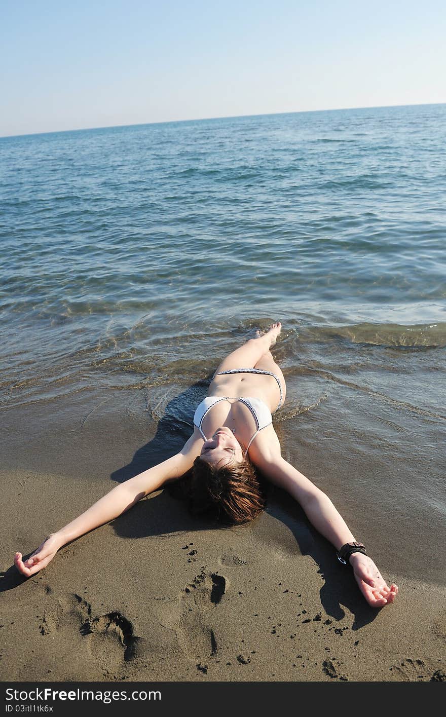 Happy young woman relax on beautiful beach at fresh summer morning and enjoy first ray of sun. Happy young woman relax on beautiful beach at fresh summer morning and enjoy first ray of sun