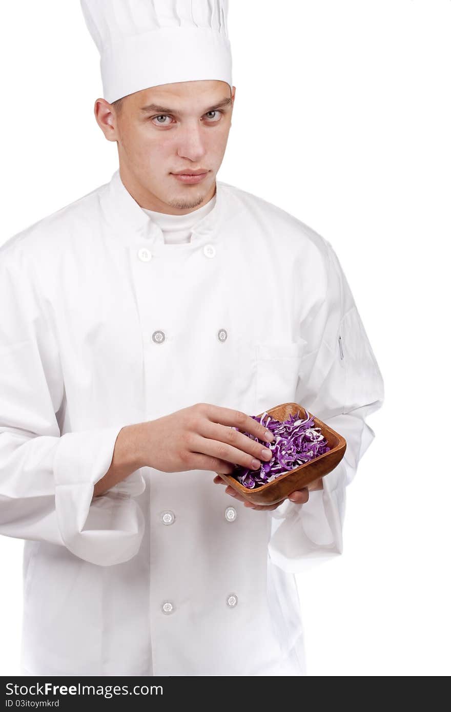 The young chef in uniform and chef's hat in his hands chopped red cabbage.