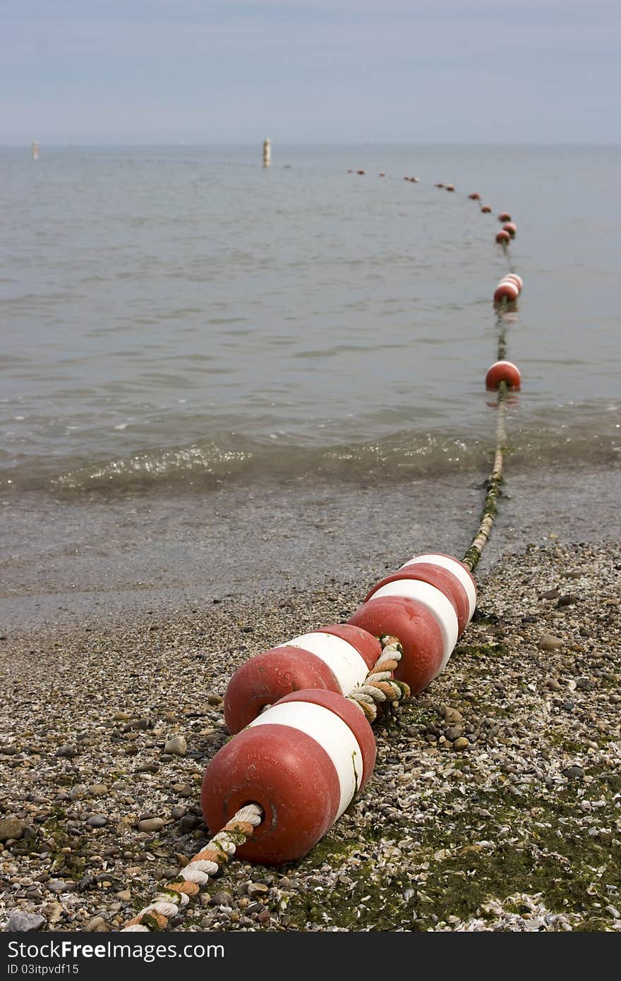 A line of buoys marking the swimming area at a beach. A line of buoys marking the swimming area at a beach.