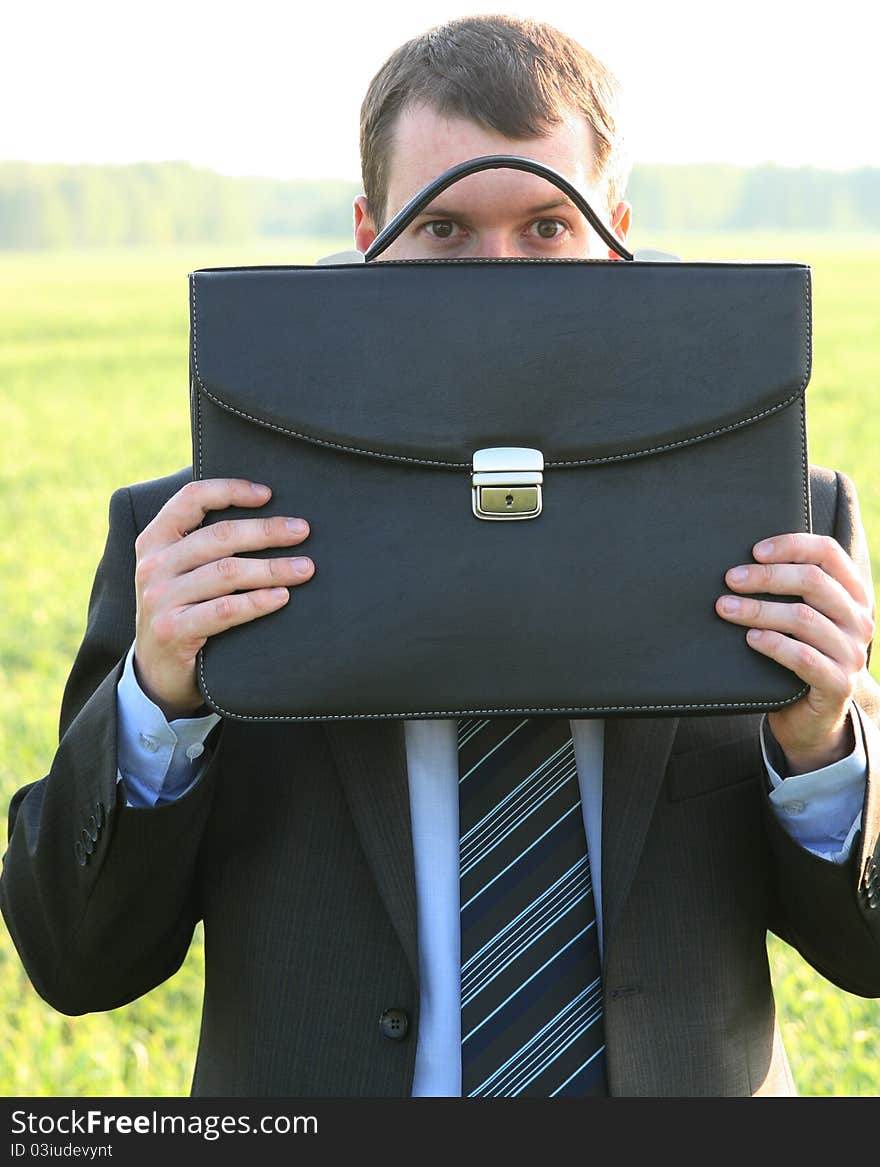 Businessman closes black briefcase in the field