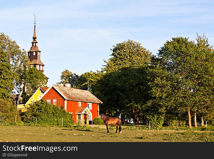 Red and yellow house, with a church behind and a horse in front. Red and yellow house, with a church behind and a horse in front.