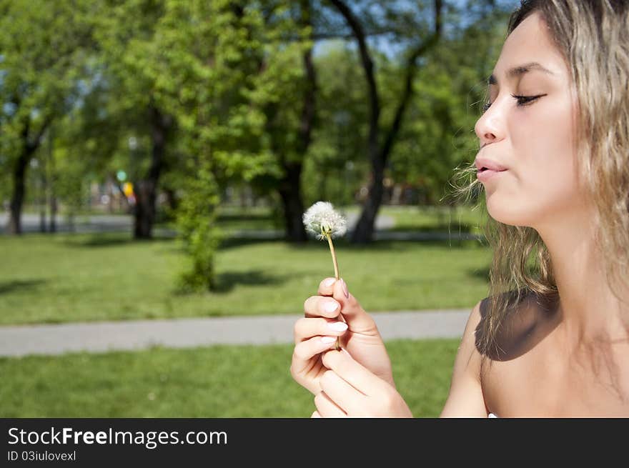 Young Girl Blowing On The Dandelion