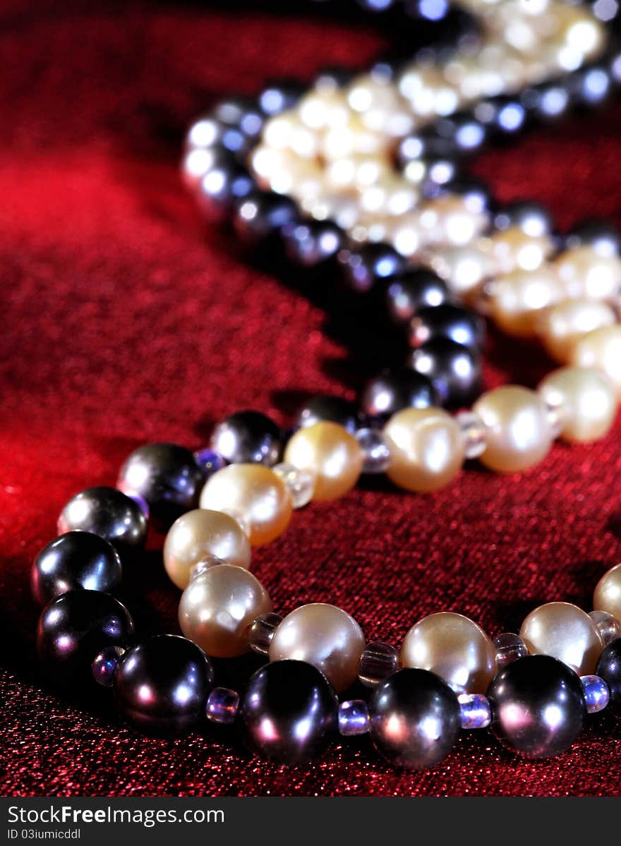 White and black Pearl necklace on a red silk, close up