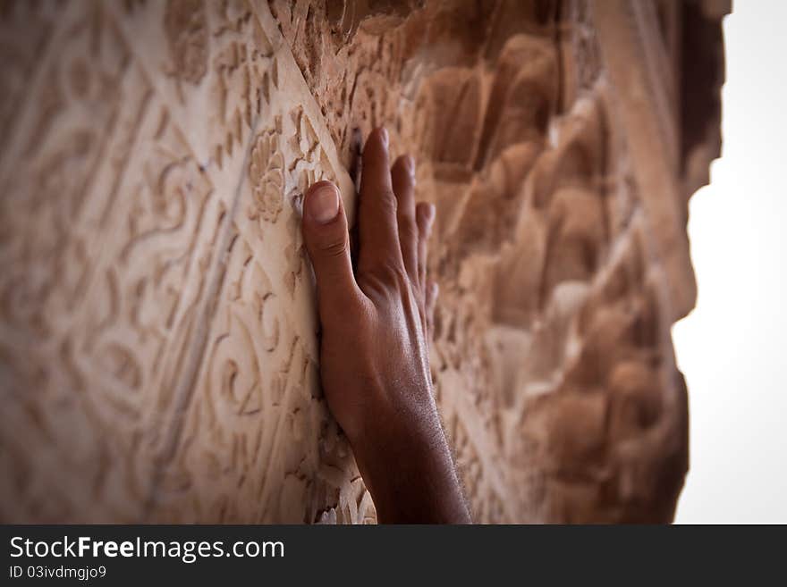 A hand reaching up to touch carvings. A hand reaching up to touch carvings