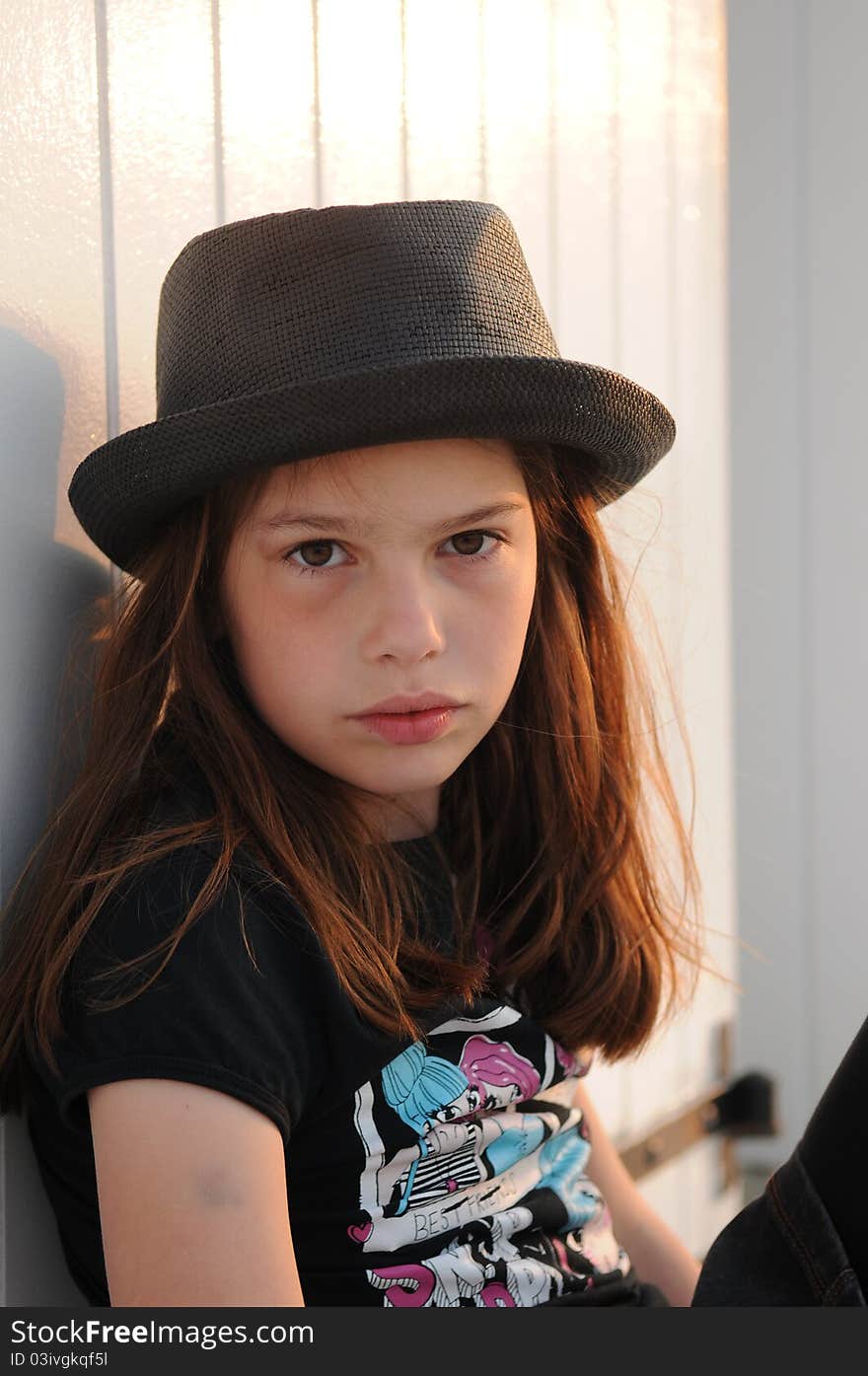 Young girl wearing black hat against beach cabin