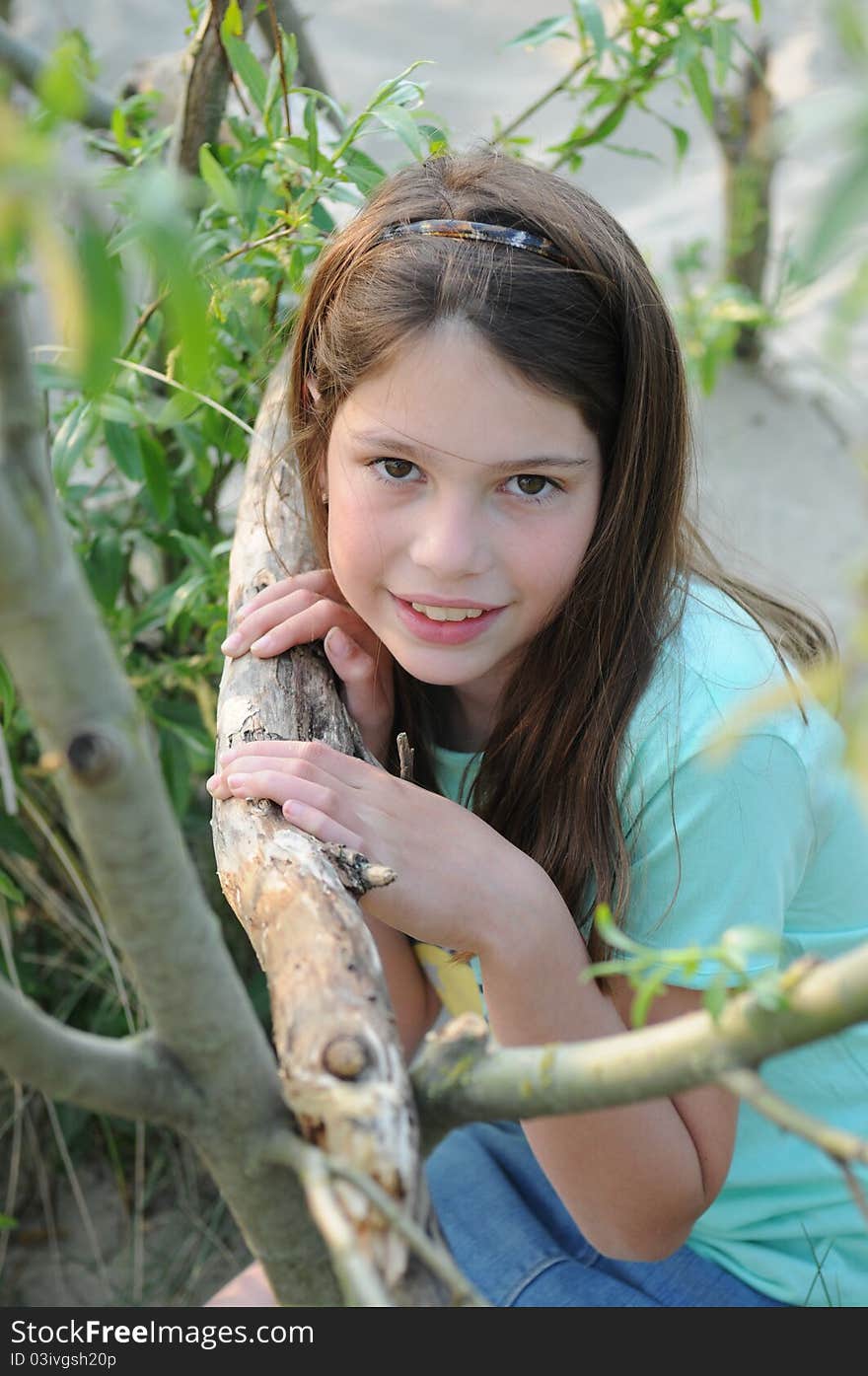 Young girl posing at a tree wearing a green shirt