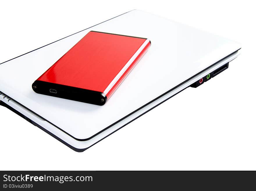 Portable red external hard disk for extra data or file storage, on top of white laptop computer with white background. Portable red external hard disk for extra data or file storage, on top of white laptop computer with white background.