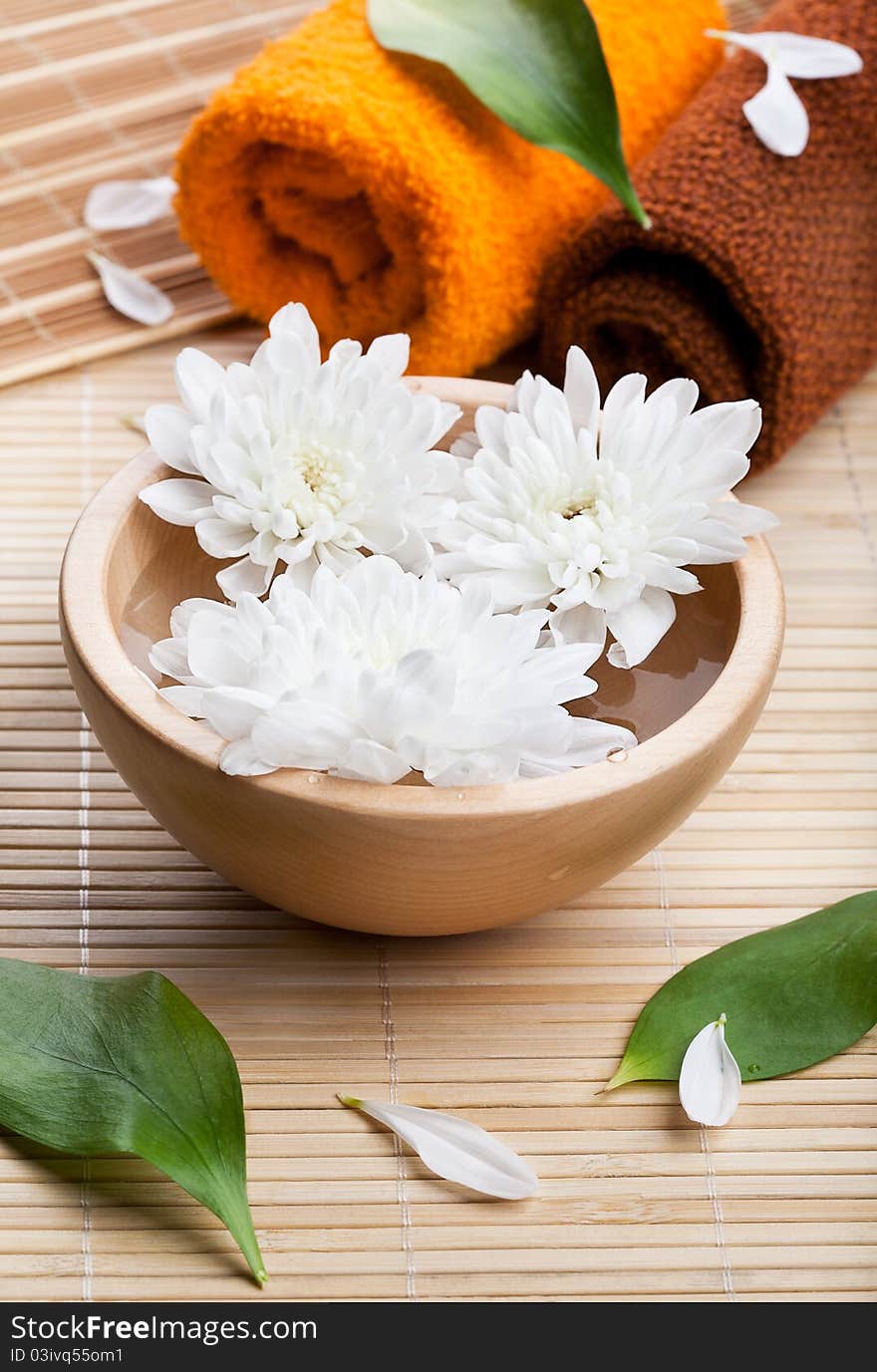 Towels and white daisies in wooden bowl. Spa and body care. Towels and white daisies in wooden bowl. Spa and body care