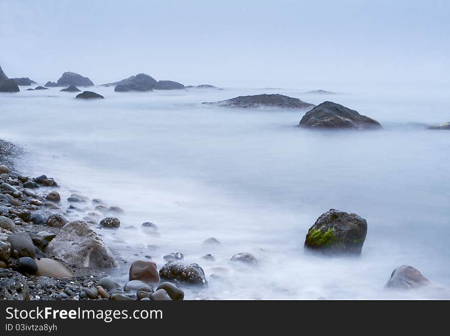 Morning sea shore with surf and rocks