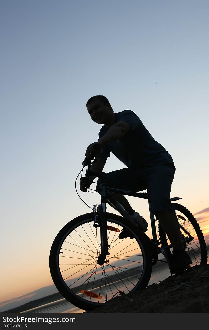 Silhouette of a cyclist riding along the beach