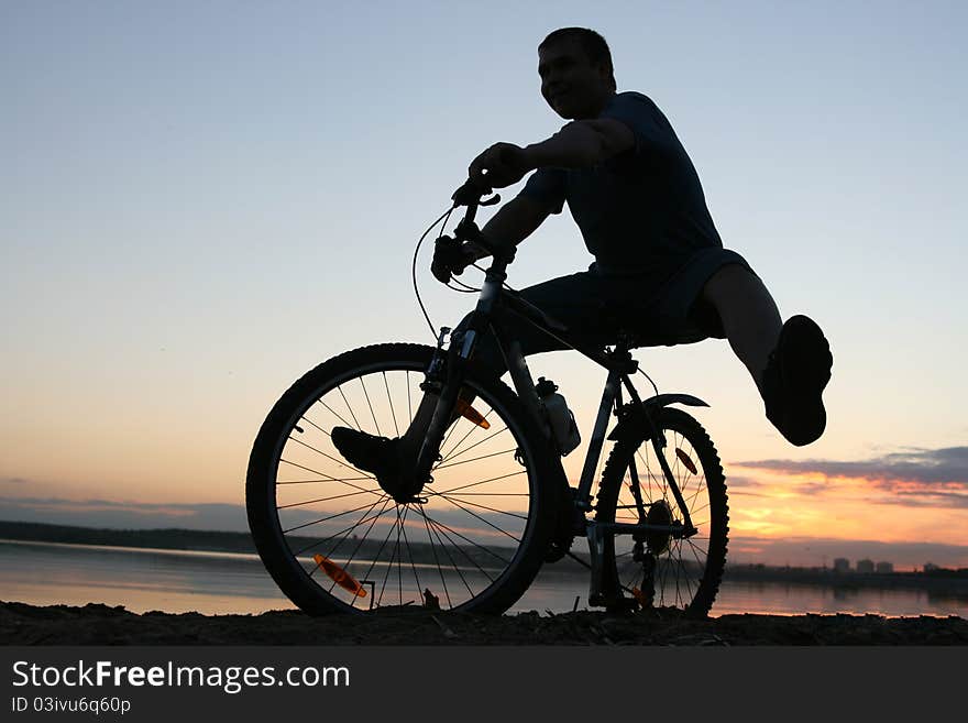 Silhouette of a cyclist riding along the beach