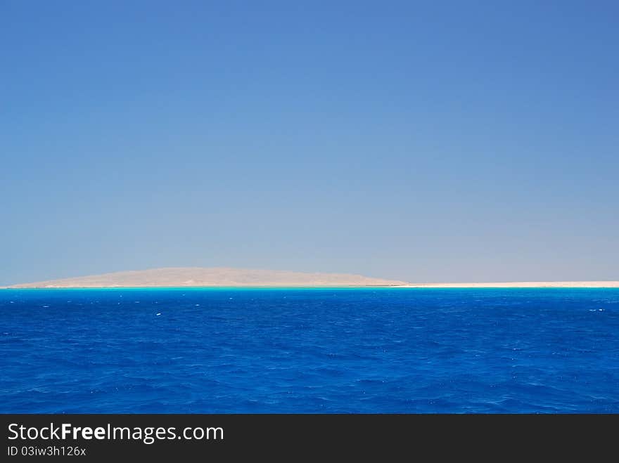 Blue sea and white sand beach on the horizon an island with. Blue sea and white sand beach on the horizon an island with