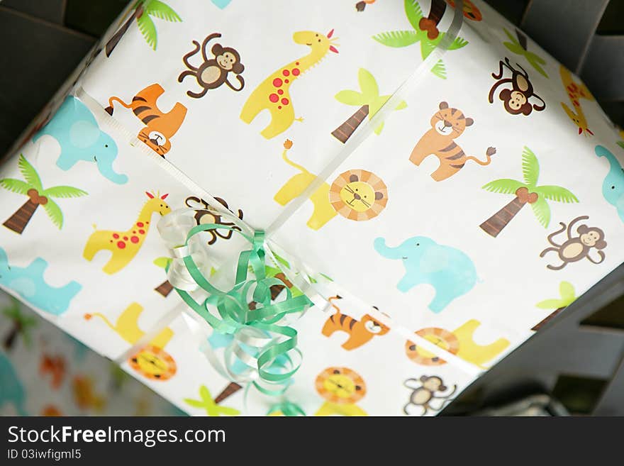 This a picture of a gift, wrapped in a children's gift warp paper. With a light blue ribbon. Picture of Lions, Palm Tress and little monkey's on the paper. This a picture of a gift, wrapped in a children's gift warp paper. With a light blue ribbon. Picture of Lions, Palm Tress and little monkey's on the paper.