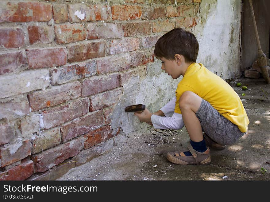 Young boy wreck an old brick wall with a hammer. Young boy wreck an old brick wall with a hammer