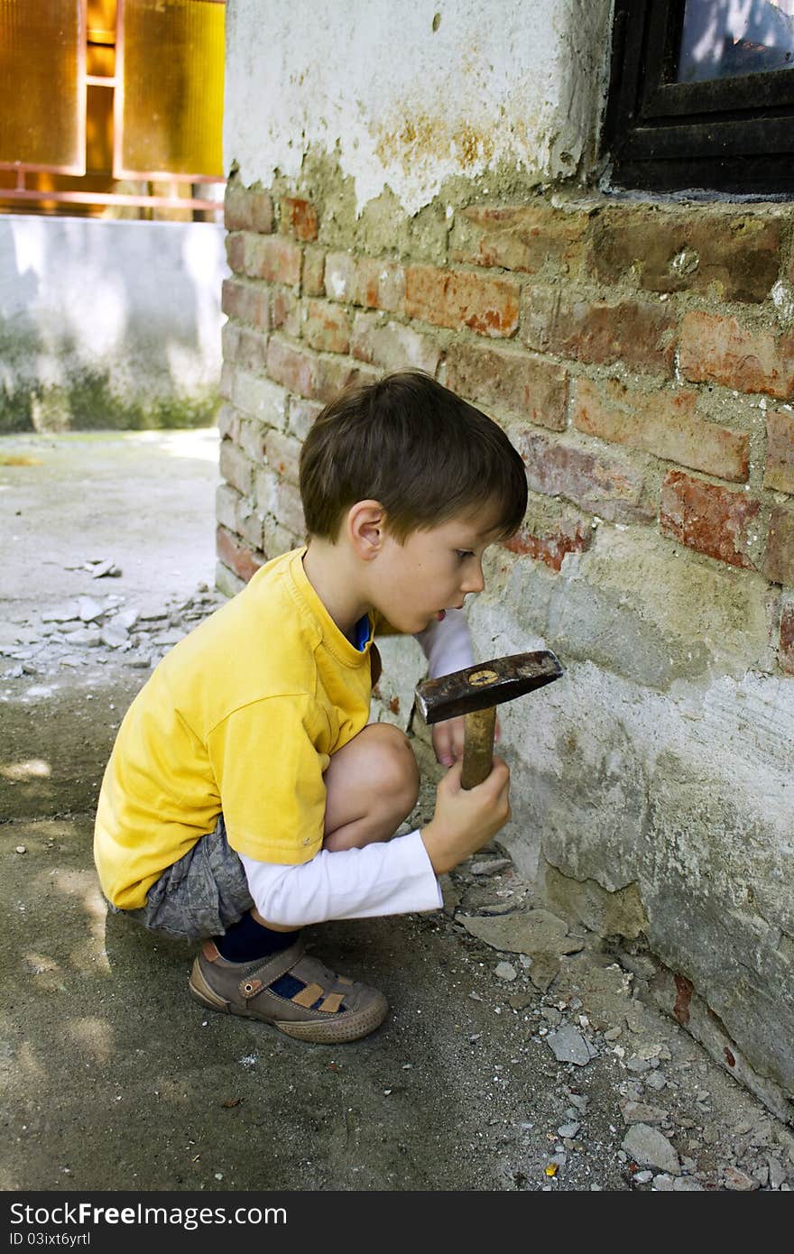 Young boy wreck an old brick wall with a hammer. Young boy wreck an old brick wall with a hammer