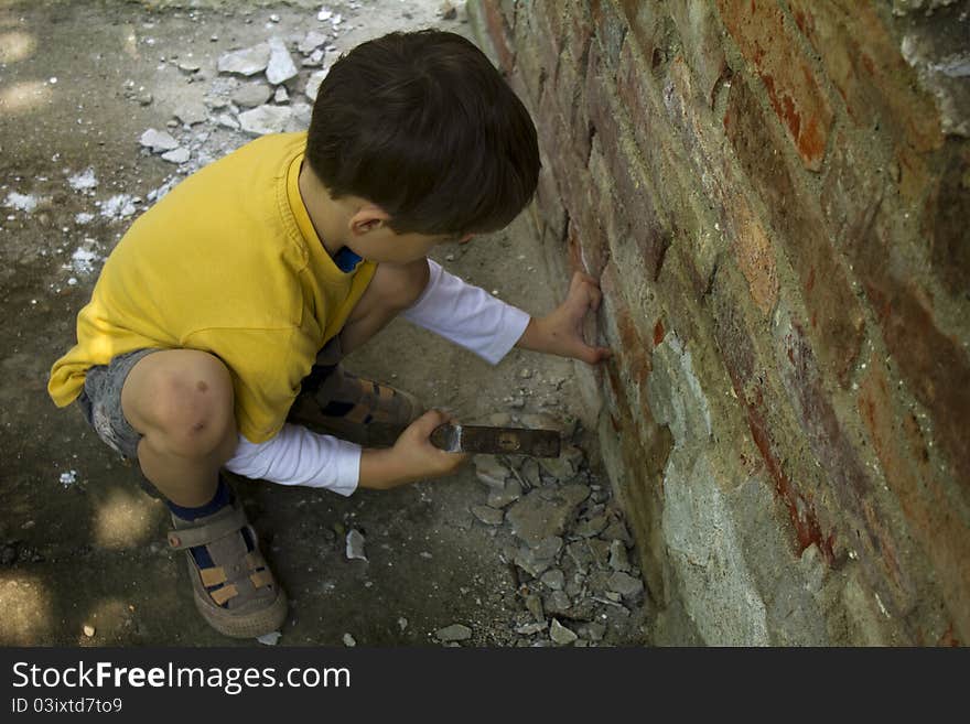 Young boy wreck an old brick wall with a hammer. Young boy wreck an old brick wall with a hammer