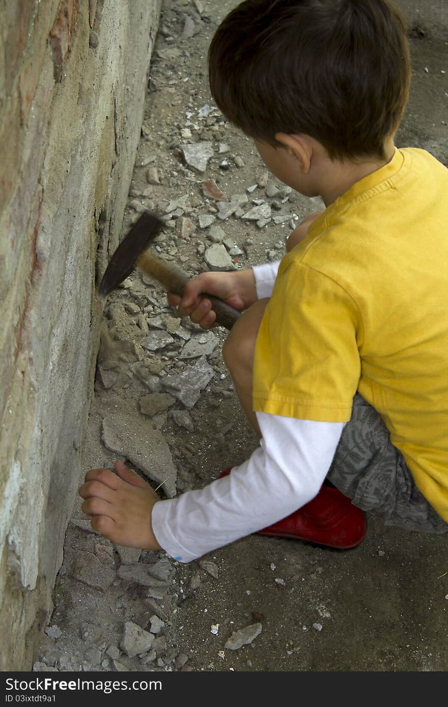 Young boy wreck an old brick wall with a hammer. Young boy wreck an old brick wall with a hammer