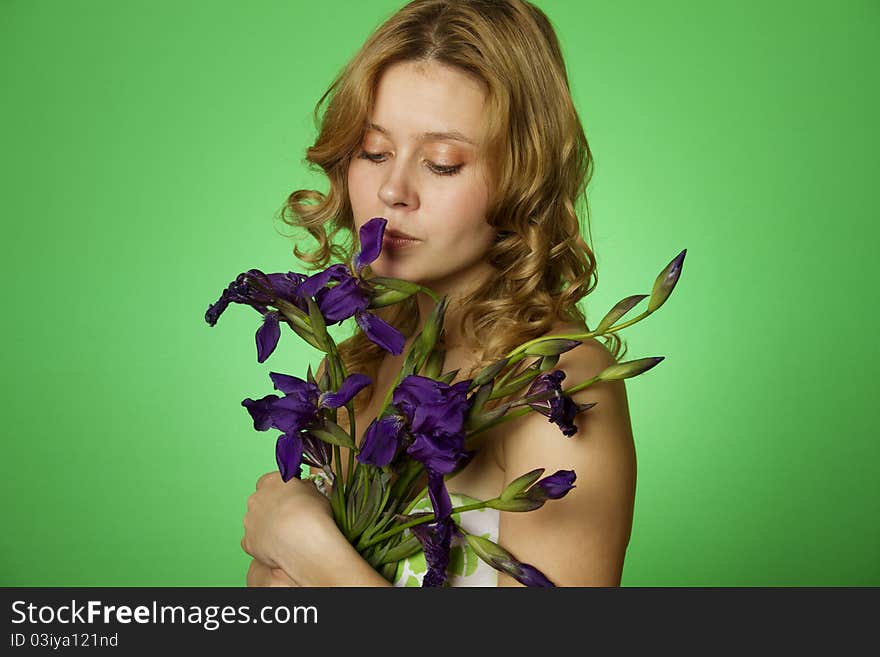 Happy close-up on a green background Happy young woman hugging a blue iris. Young Woman Hugging Flower. Happy close-up on a green background Happy young woman hugging a blue iris. Young Woman Hugging Flower