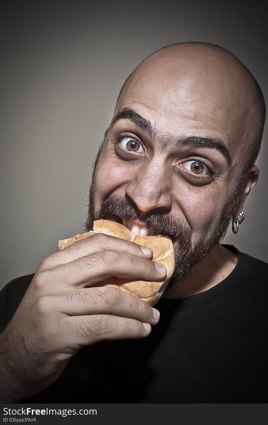 Happy man eating a sandwich on dark background