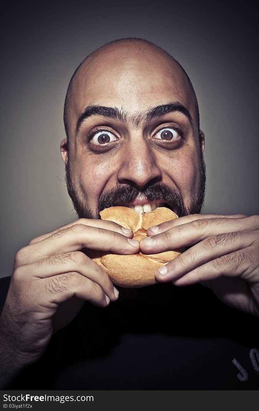 Happy man eating a sandwich on dark background