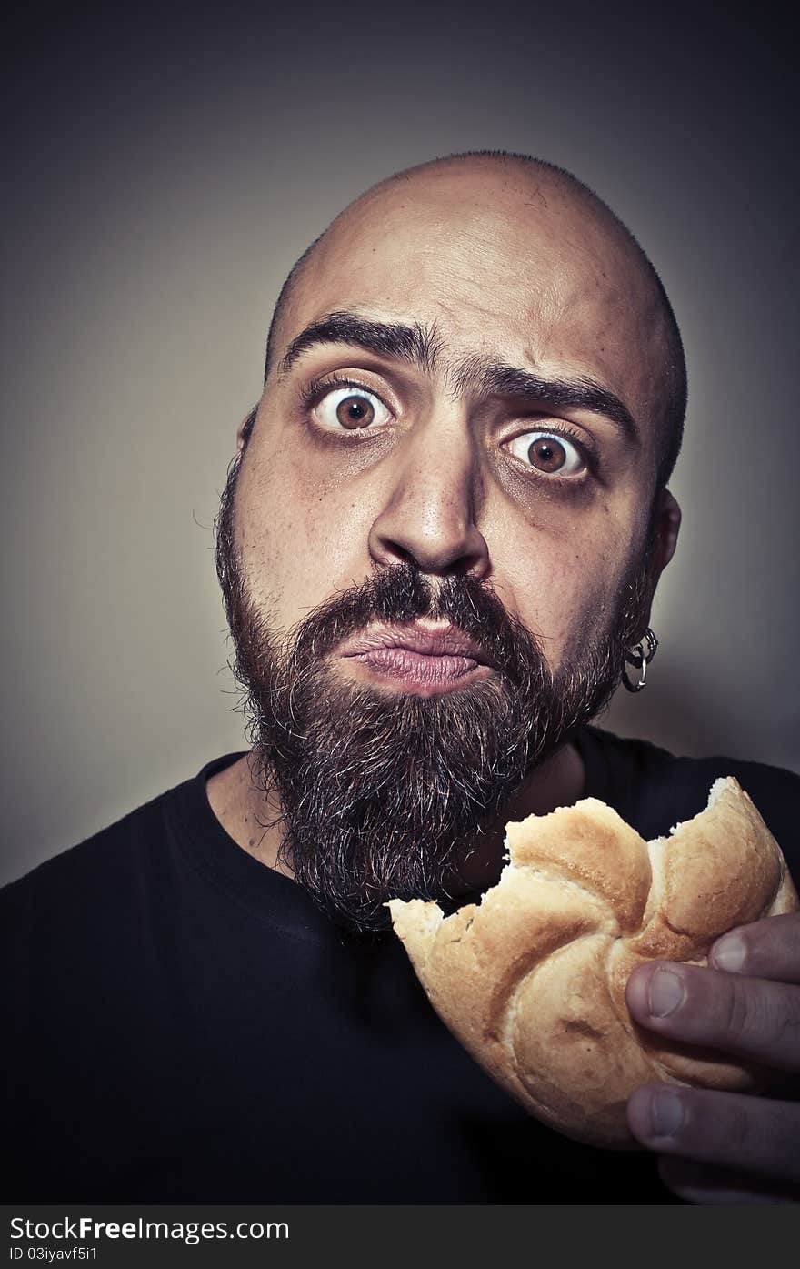 Happy man eating a sandwich on dark background