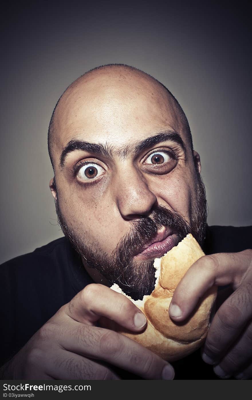 Funny man eating a sandwich on dark background