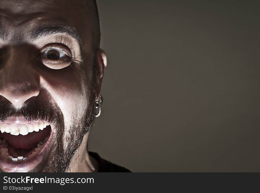 Mid-frontal portrait of a man yelling on grey background