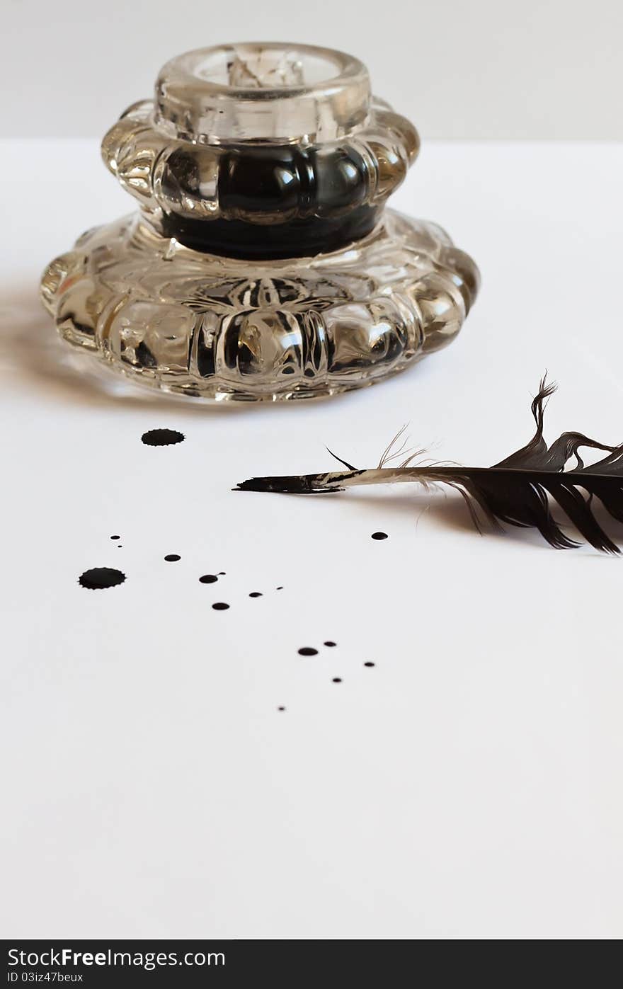 Feather and inkwell on white background