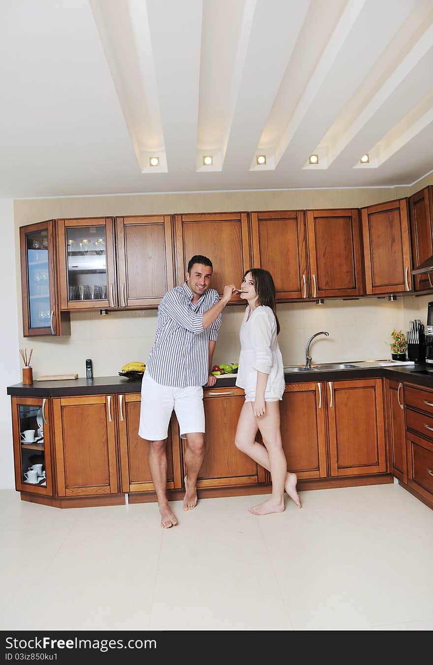 Happy young couple have fun in modern wooden kitchen indoor while preparing fresh food. Happy young couple have fun in modern wooden kitchen indoor while preparing fresh food