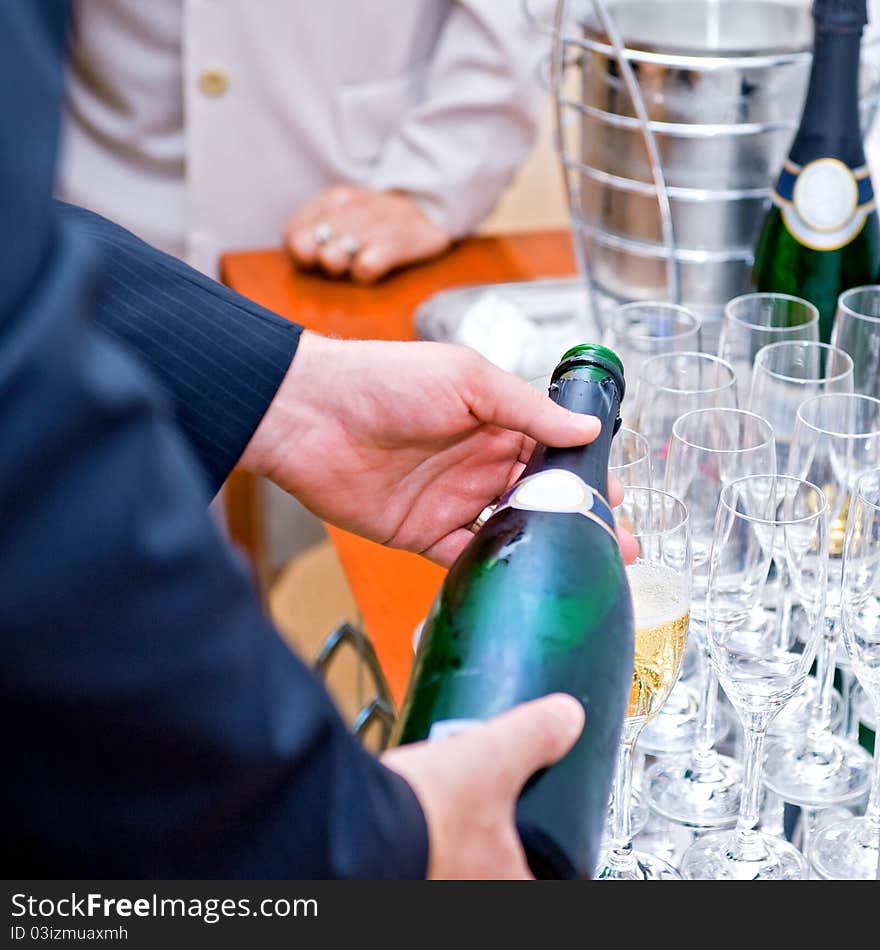 Man in suite pouring champagne to glasses