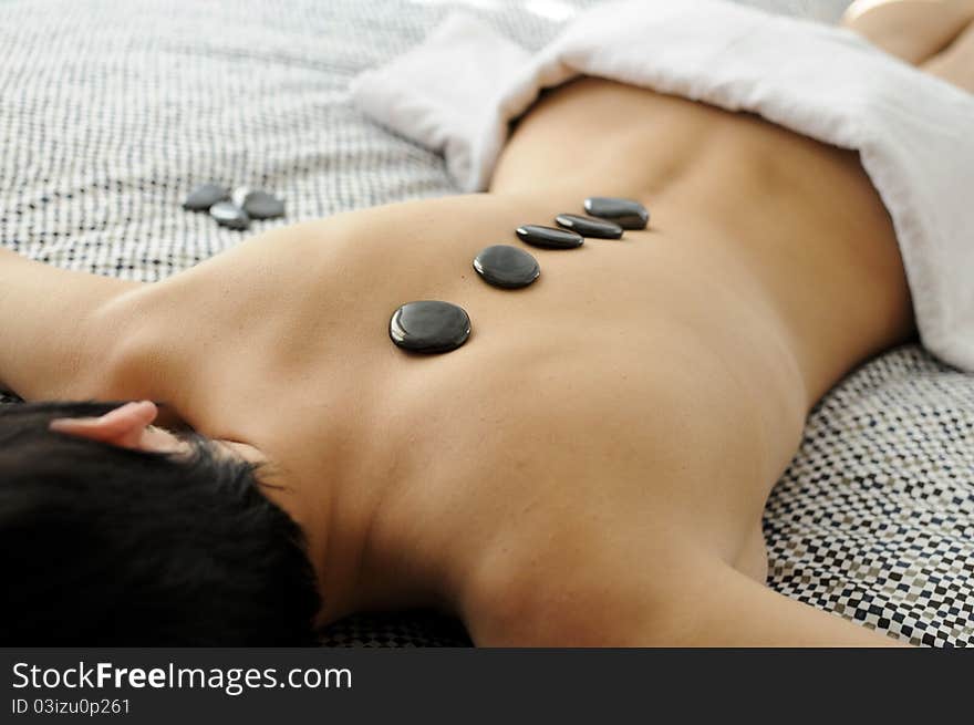 Woman getting hot stone massage with black pebbles