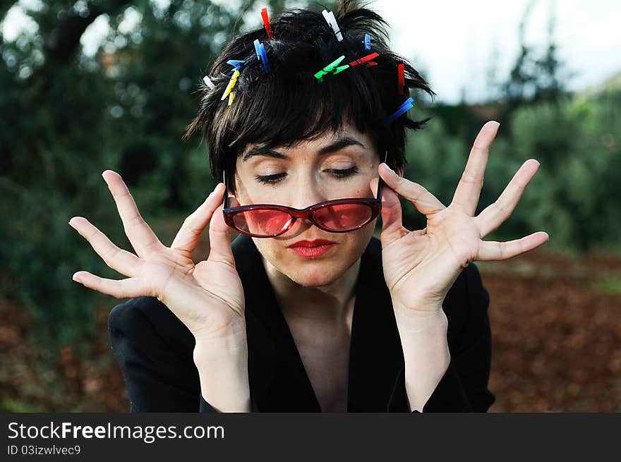 Funny picture of a girl with her hair adorned with clothespins, wearing cheerful sunglasses subject with her hands. Funny picture of a girl with her hair adorned with clothespins, wearing cheerful sunglasses subject with her hands.