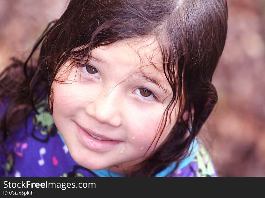 Portrait of a pretty little girl with wet hair smiling up