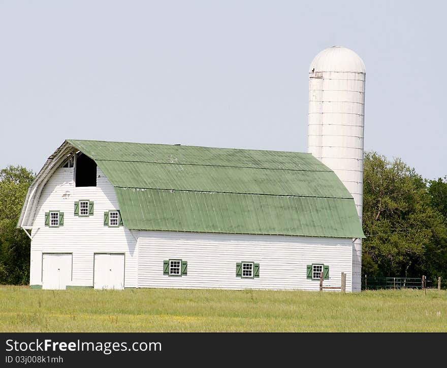 Beautiful white barn with green roof in the summer